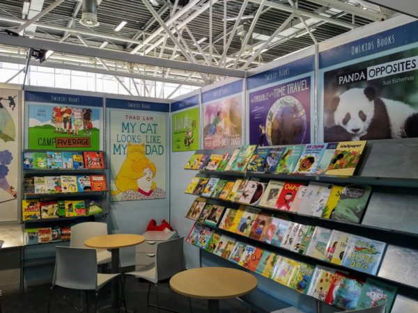 Brightly coloured children's books line the shelves of an exhibition booth.