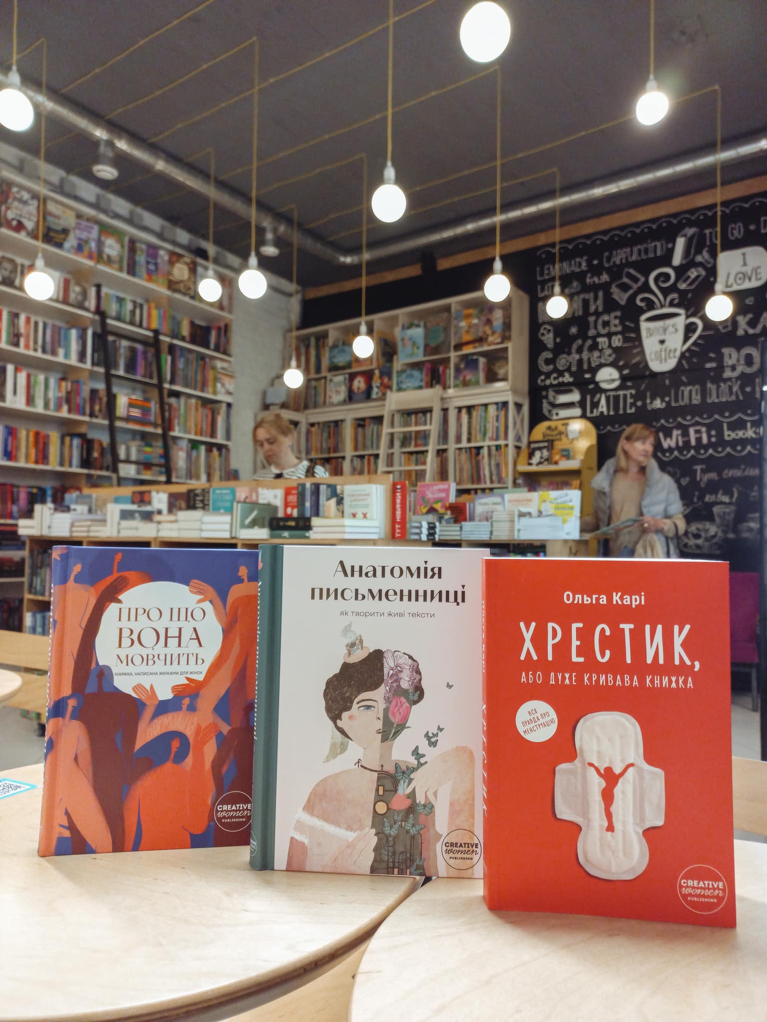 Three Ukrainian books standing on a table in a bookstore.